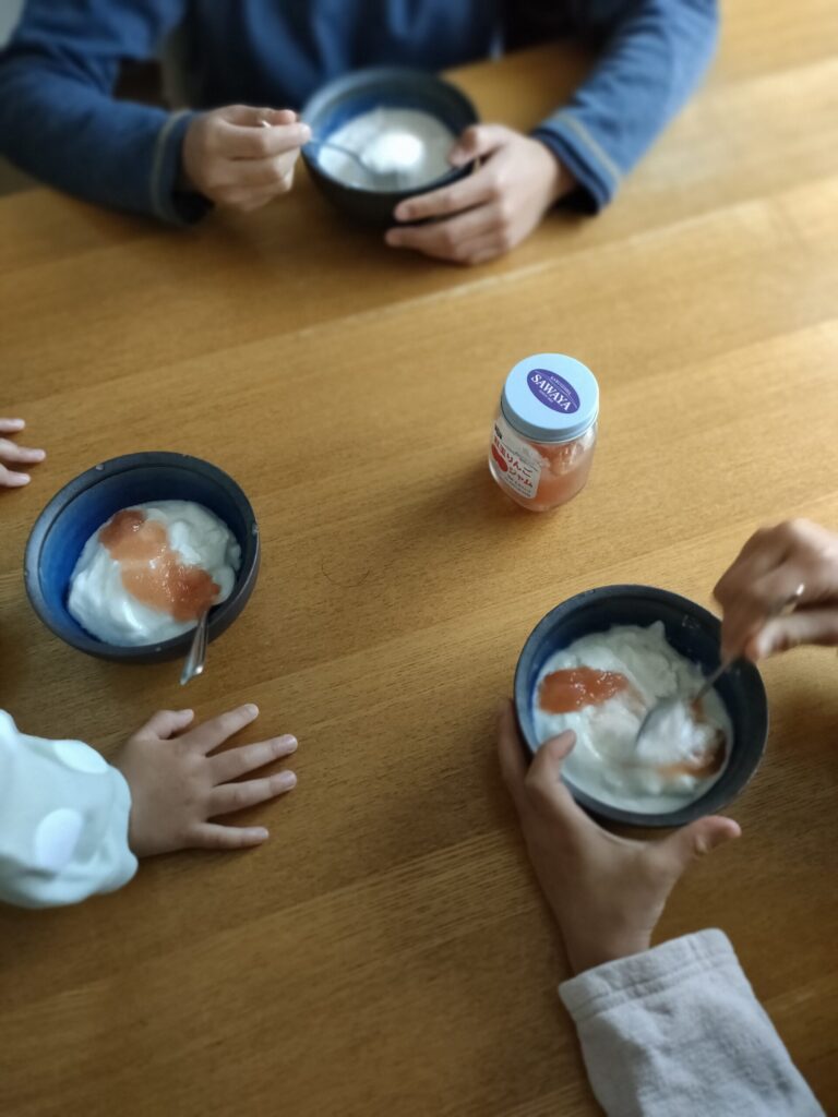リンゴジャム入りヨーグルトを食べる子どもたちのおやつの時間