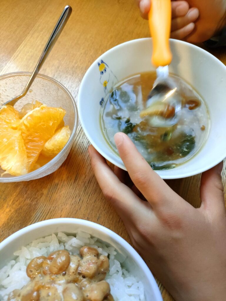 味噌汁や納豆ごはんを並べた子どもの朝食を横から撮影した様子
