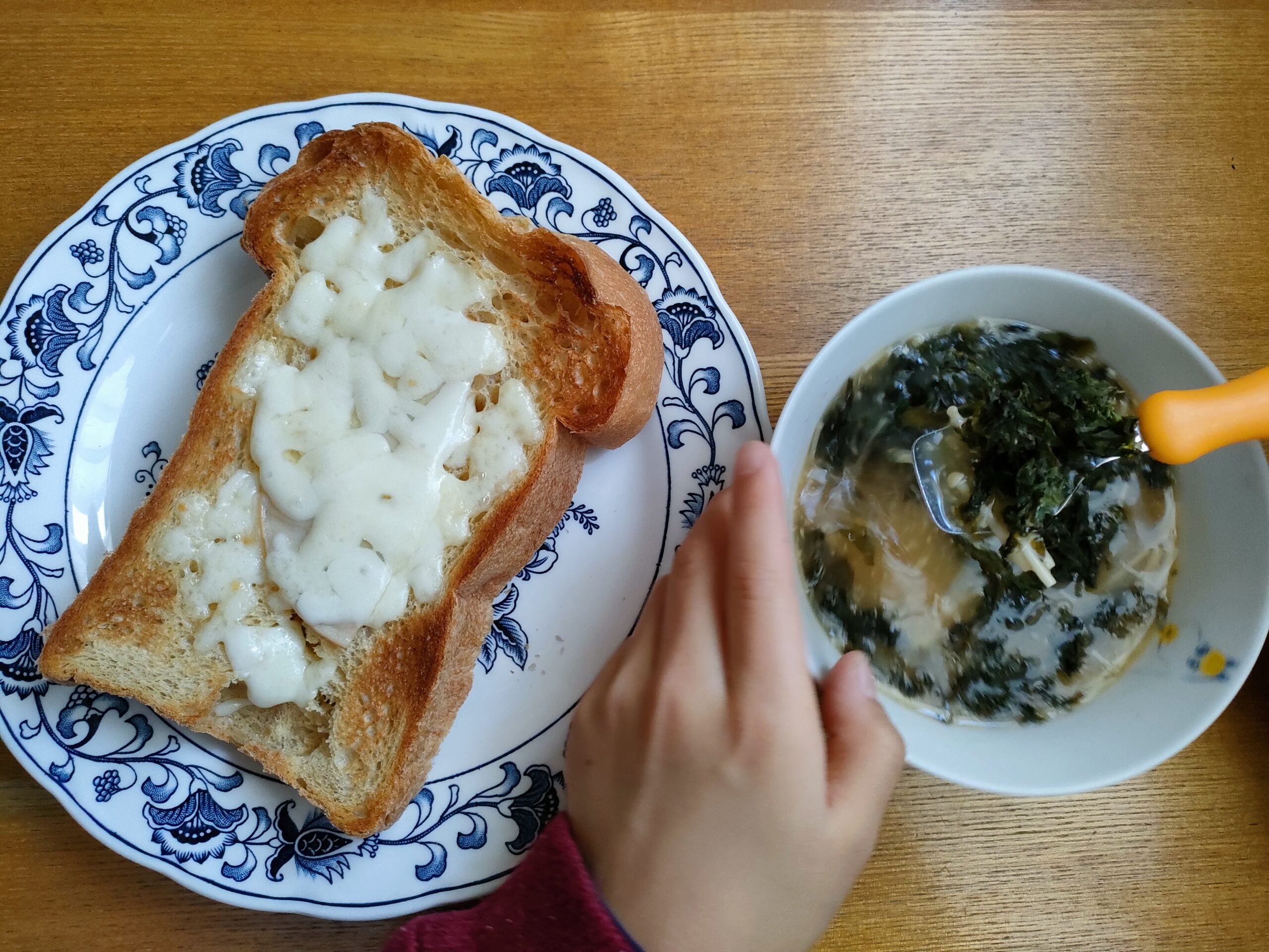 パンと味噌汁が並ぶ朝食で子どもが食事をしようとしている様子