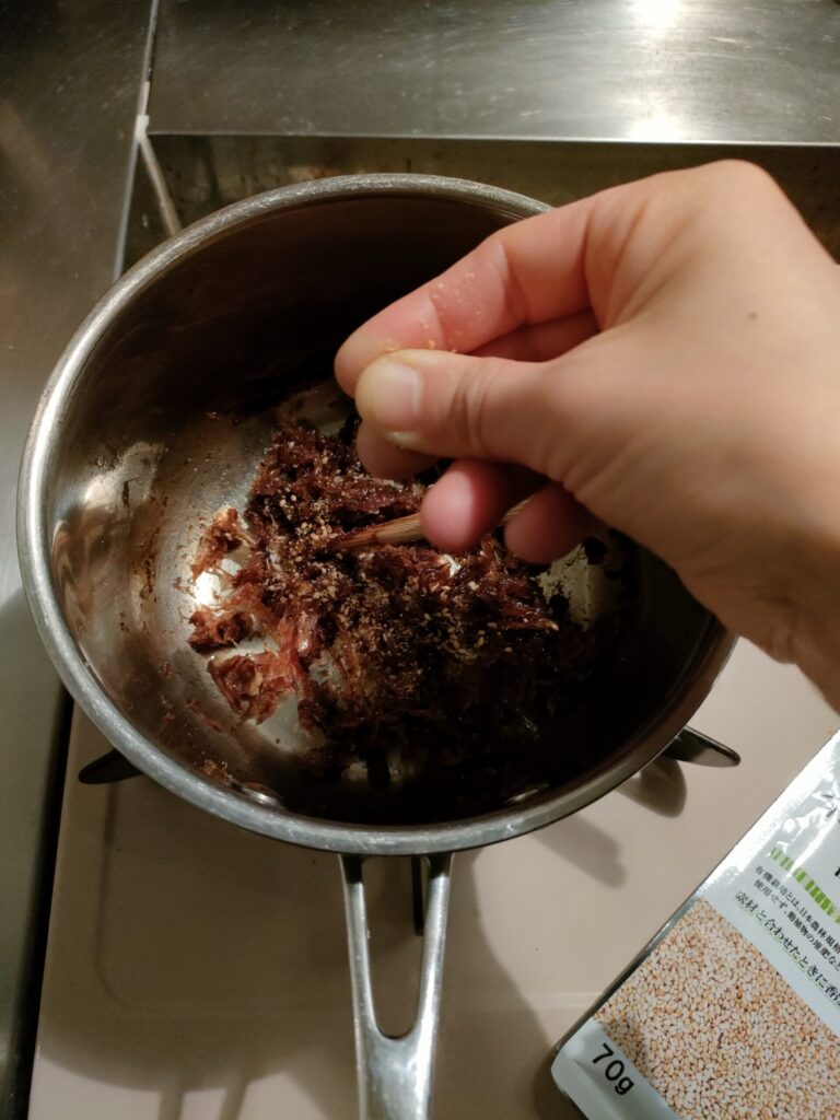 指でひねったごまをおかかふりかけに加える様子