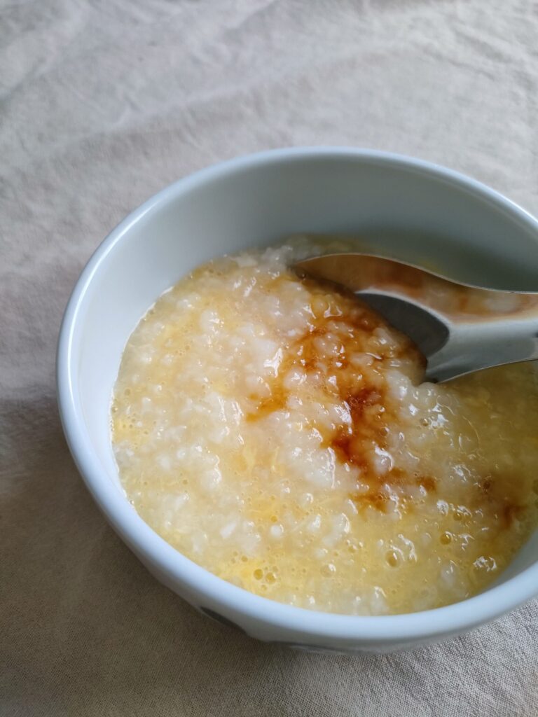 卵がゆに醤油をたらしている様子
