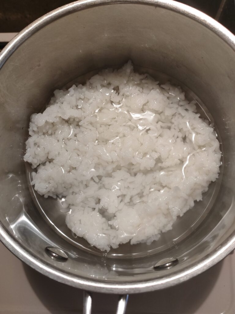 鍋に炊いたごはんと水を入れて、お粥を作る準備をしている様子