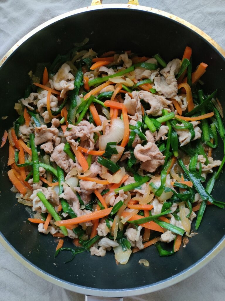 豚肉と玉ねぎ、人参、ニラを炒めて味付けが完成し、フライパンの中で仕上がった簡単プルコギの様子