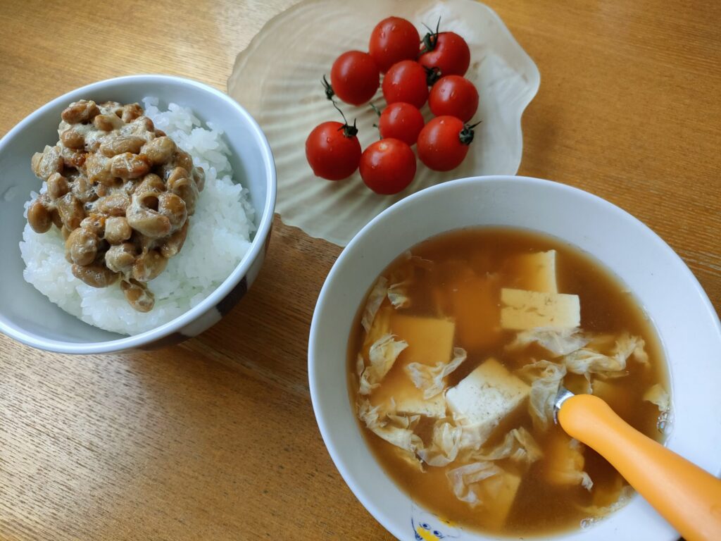 納豆ご飯と豆腐・卵入り味噌汁、ミニトマトを添えた子どもの朝ごはん