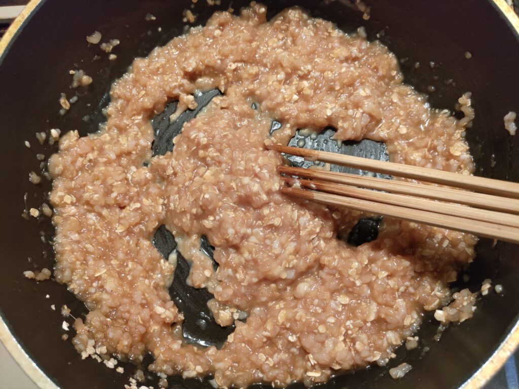 鶏そぼろの鶏ひき肉と調味料をフライパンで加熱しながら混ぜているところ。