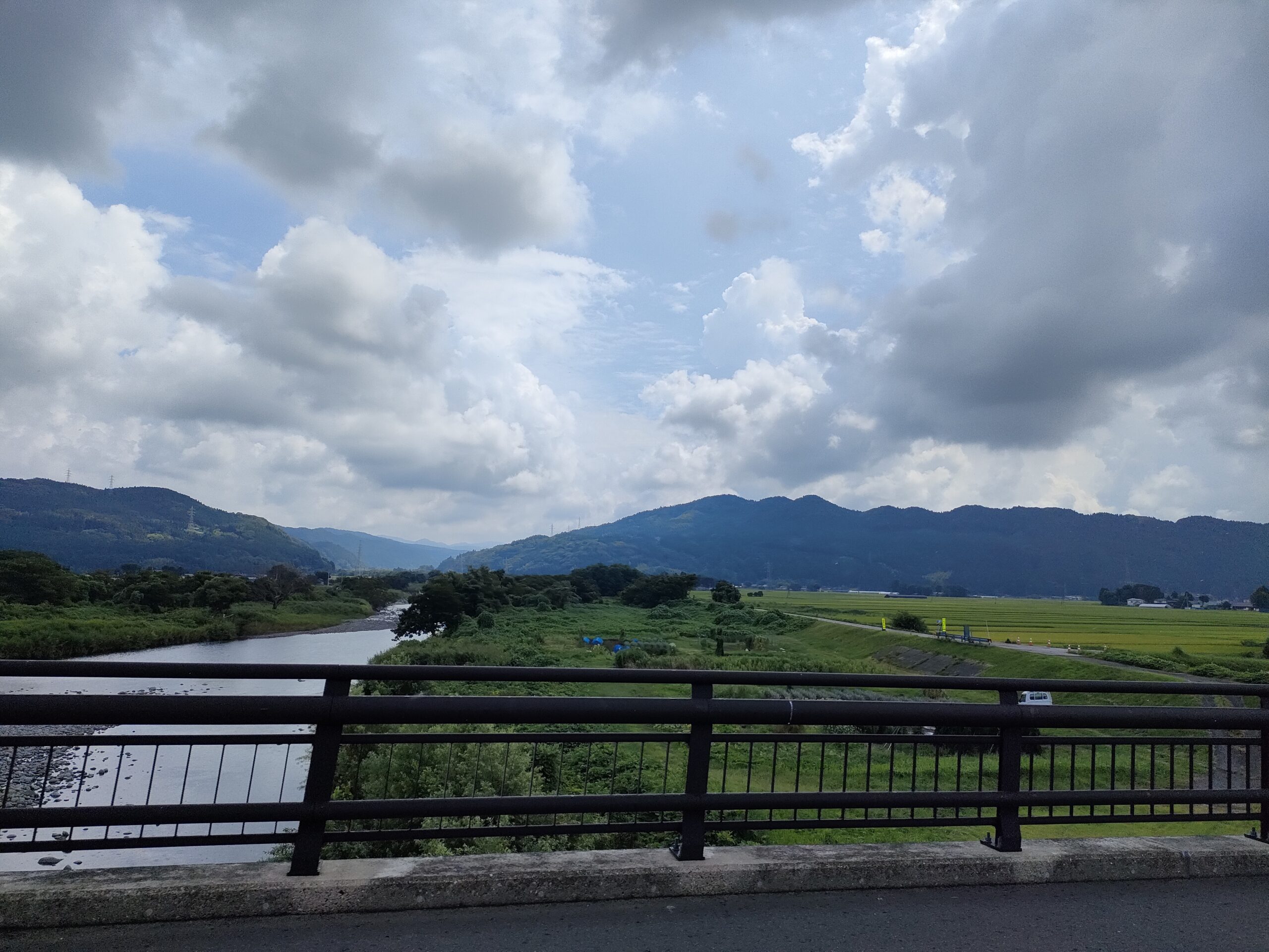 山を背景に田んぼと川が広がる、のどかな田園風景